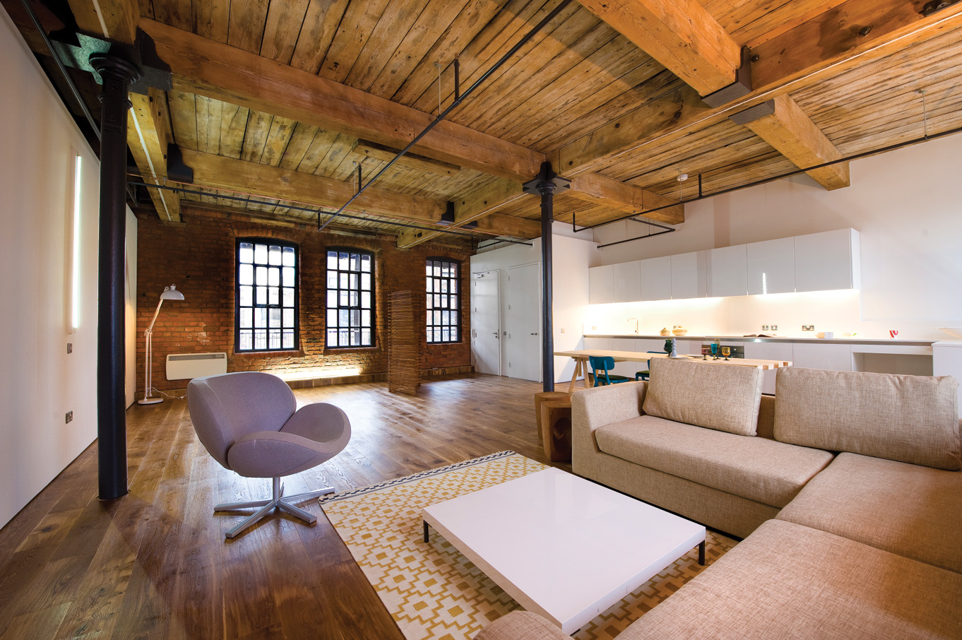 Empty loft shell — exposed brick, timber ceiling, cast iron columns, oak floor