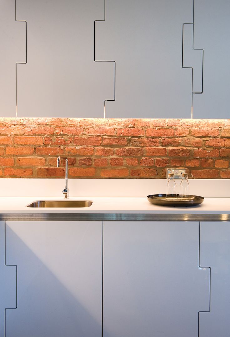 Bespoke kitchen detail — stepped joinery panels, backlit brick splashback