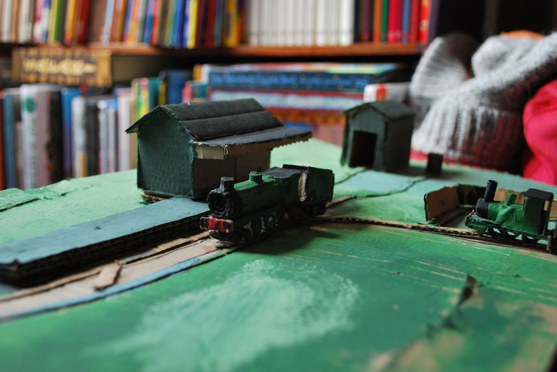 Handmade cardboard train station with locomotives