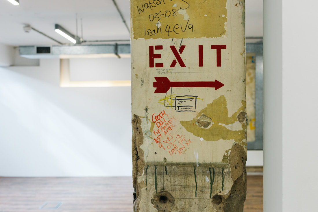 Distressed original column featuring an old painted EXIT sign and graffiti
