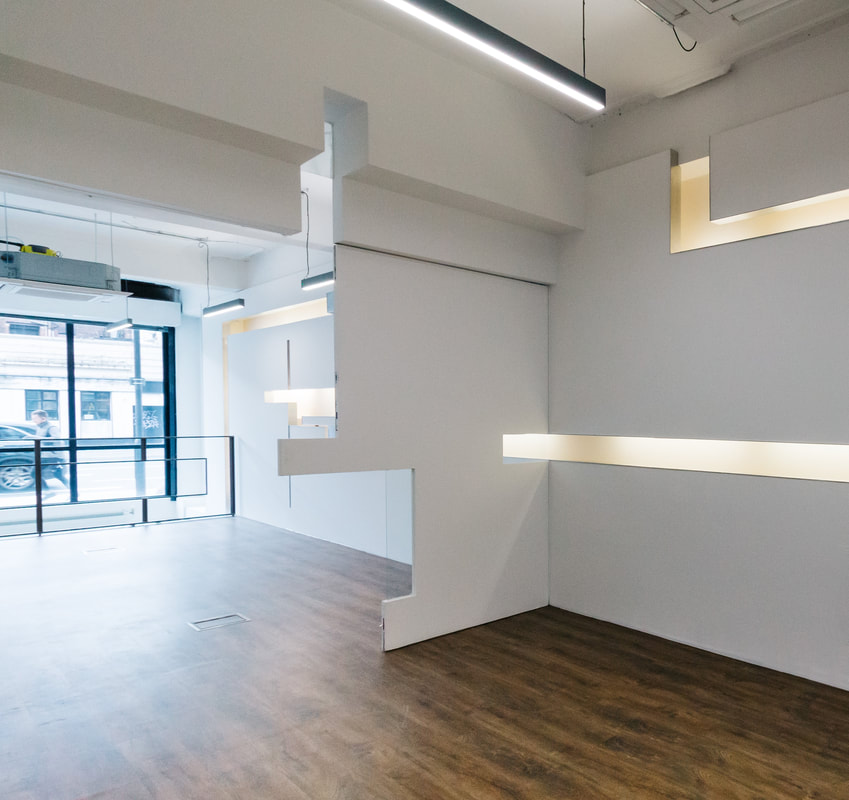 Thick white partition wall with deep geometric cuts and integrated lighting