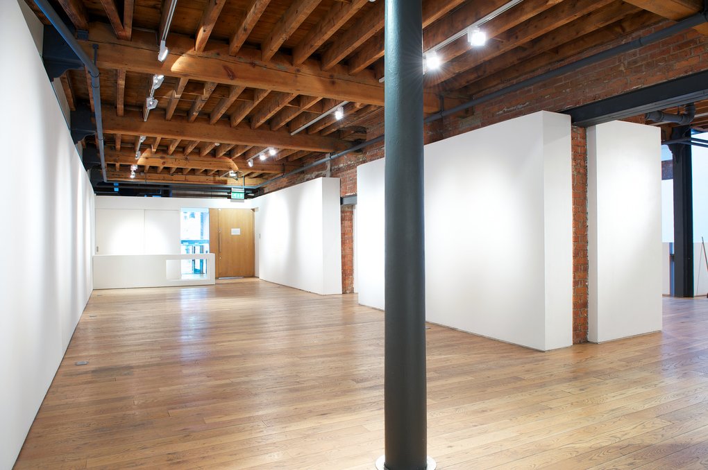Gallery wide view — columns, white walls, timber beams, oak floor