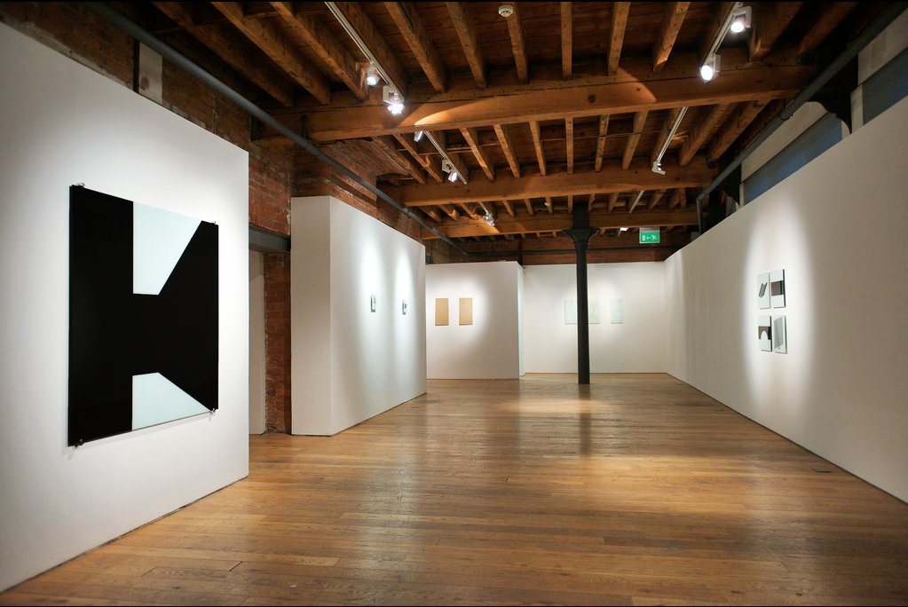 Gallery with artwork — exhibition installed between white walls and cast iron columns