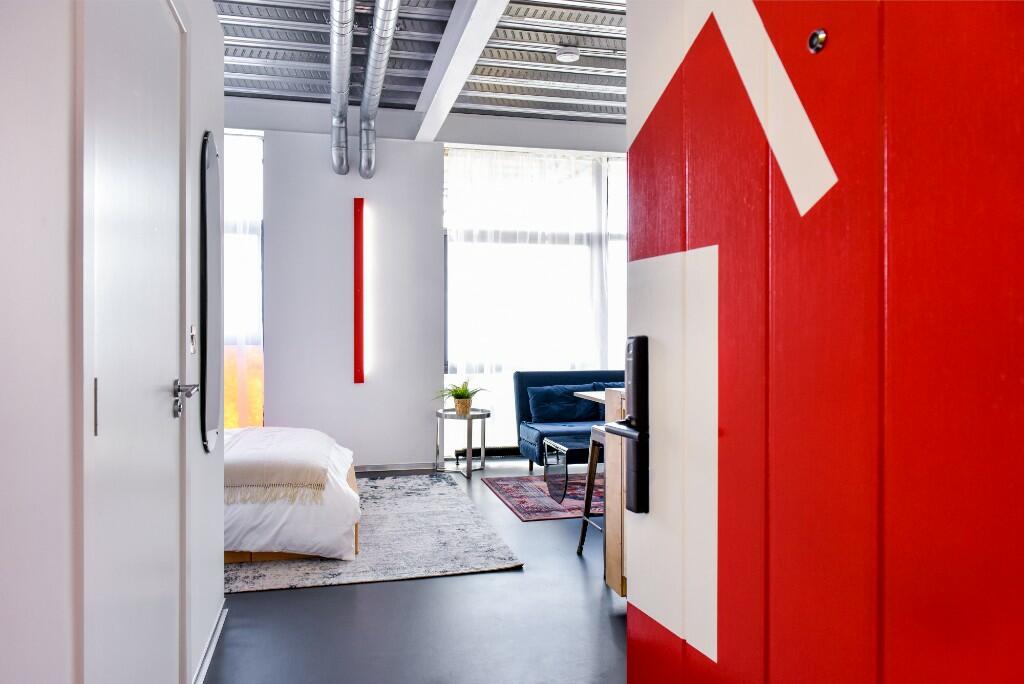 Apartment entry — red supergraphic door opening to bedroom and living space