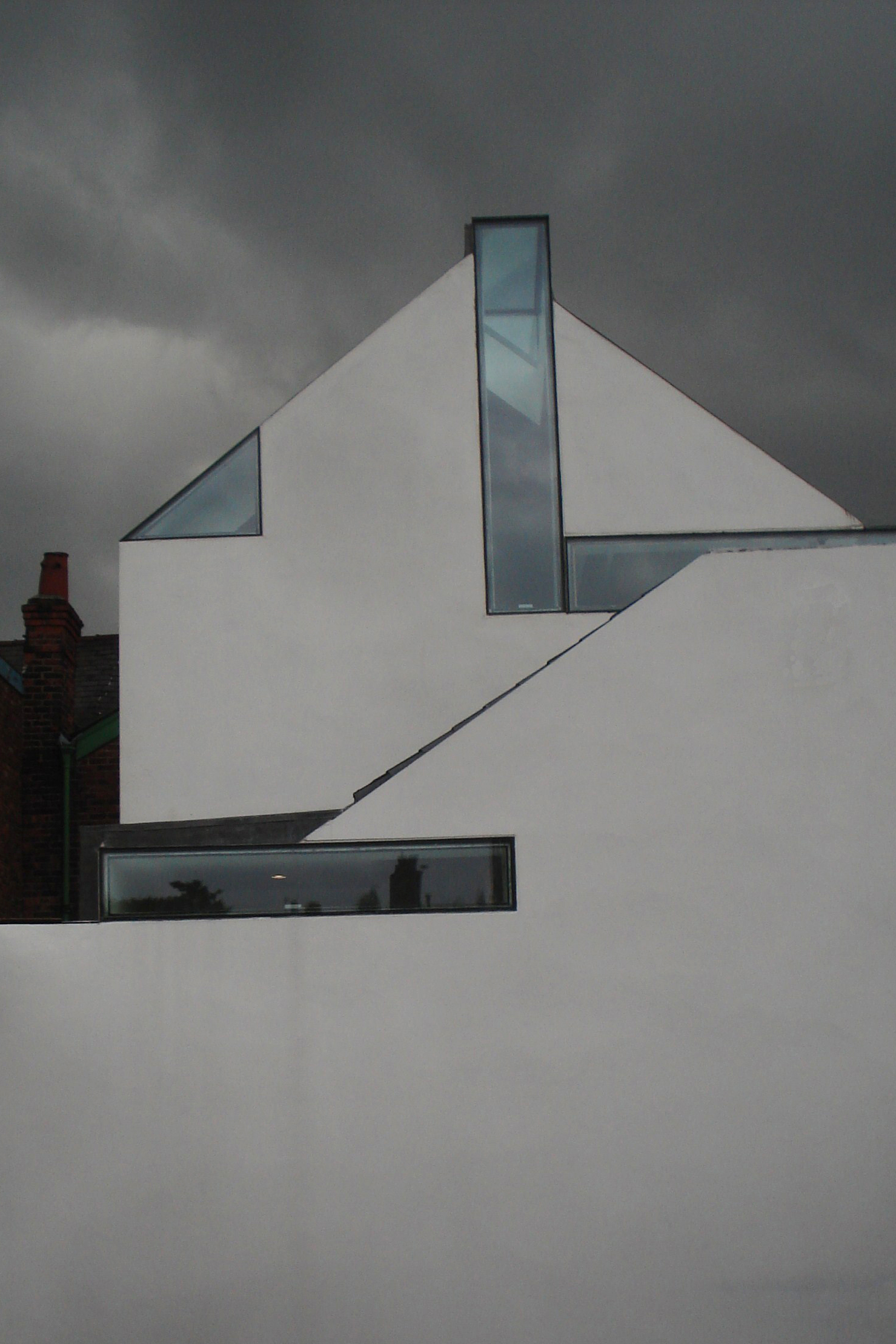 White angular roofscape with glass slot against overcast sky