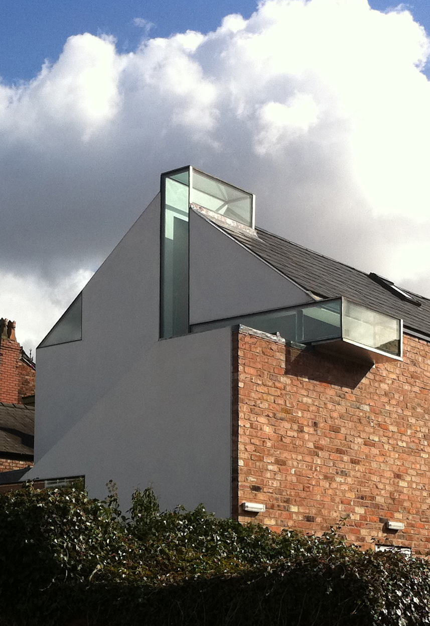 White render extension rising above Victorian brick, glass slots