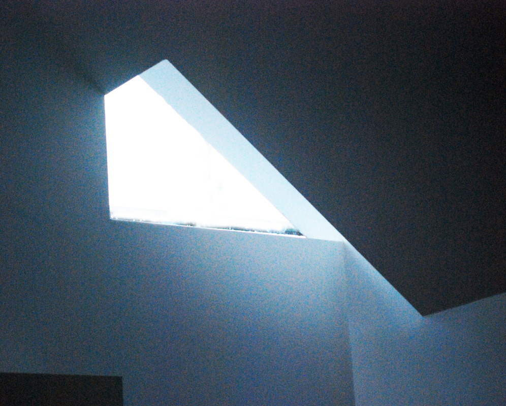 Triangular rooflight — sharp beam of daylight in dark stairwell