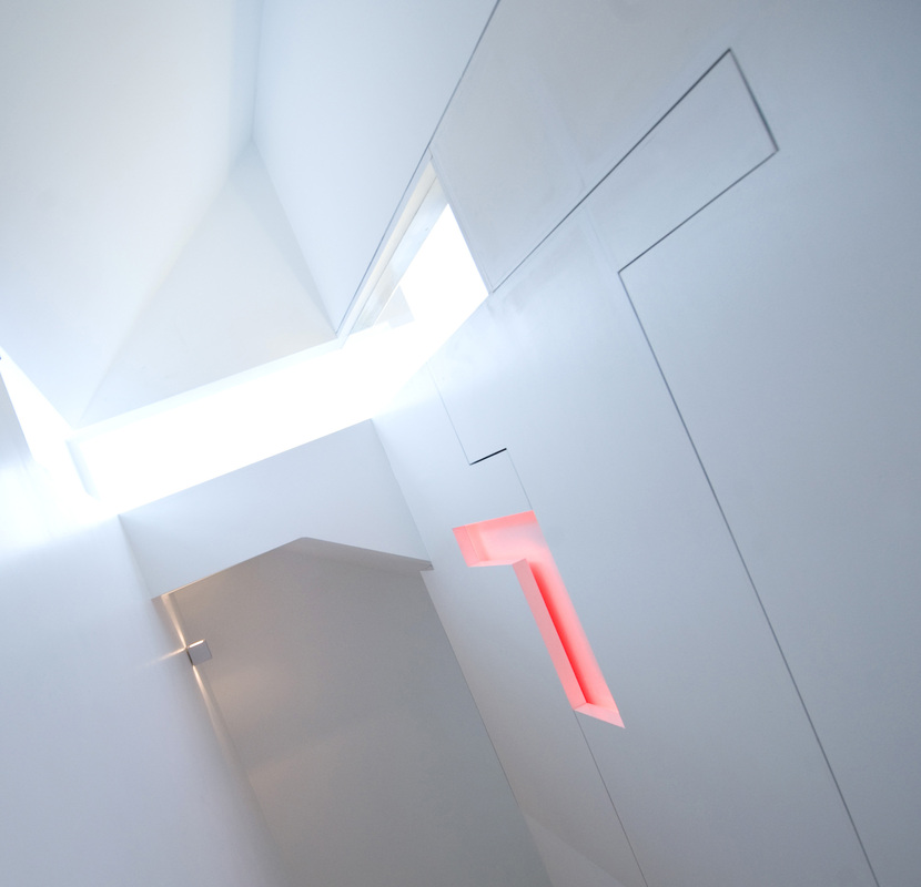 Stairwell — skylight above, illuminated red cross in white wall