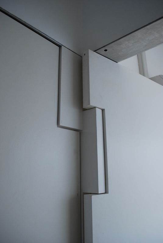 Wall junction detail — interlocking stepped panels, shadow lines