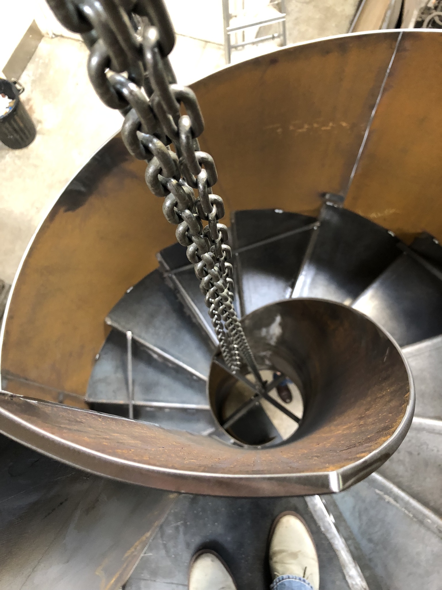 Top-down construction view of the raw steel stair being lowered by chains