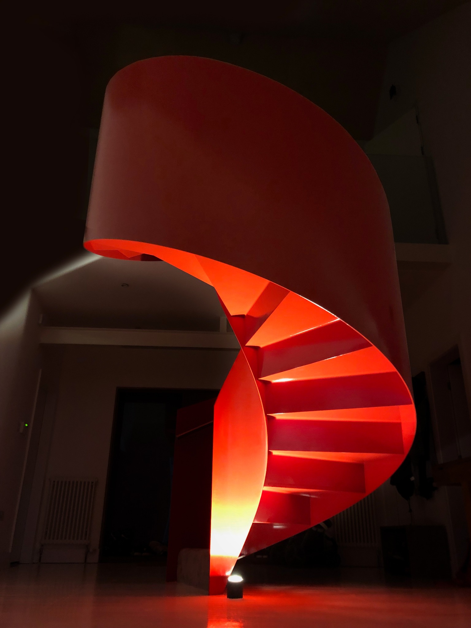 The red steel staircase dramatically illuminated from below in the dark