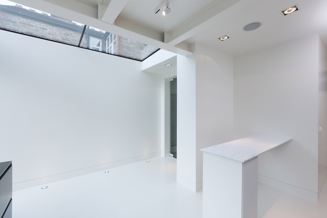 Clean white architectural surfaces beneath a large glass skylight