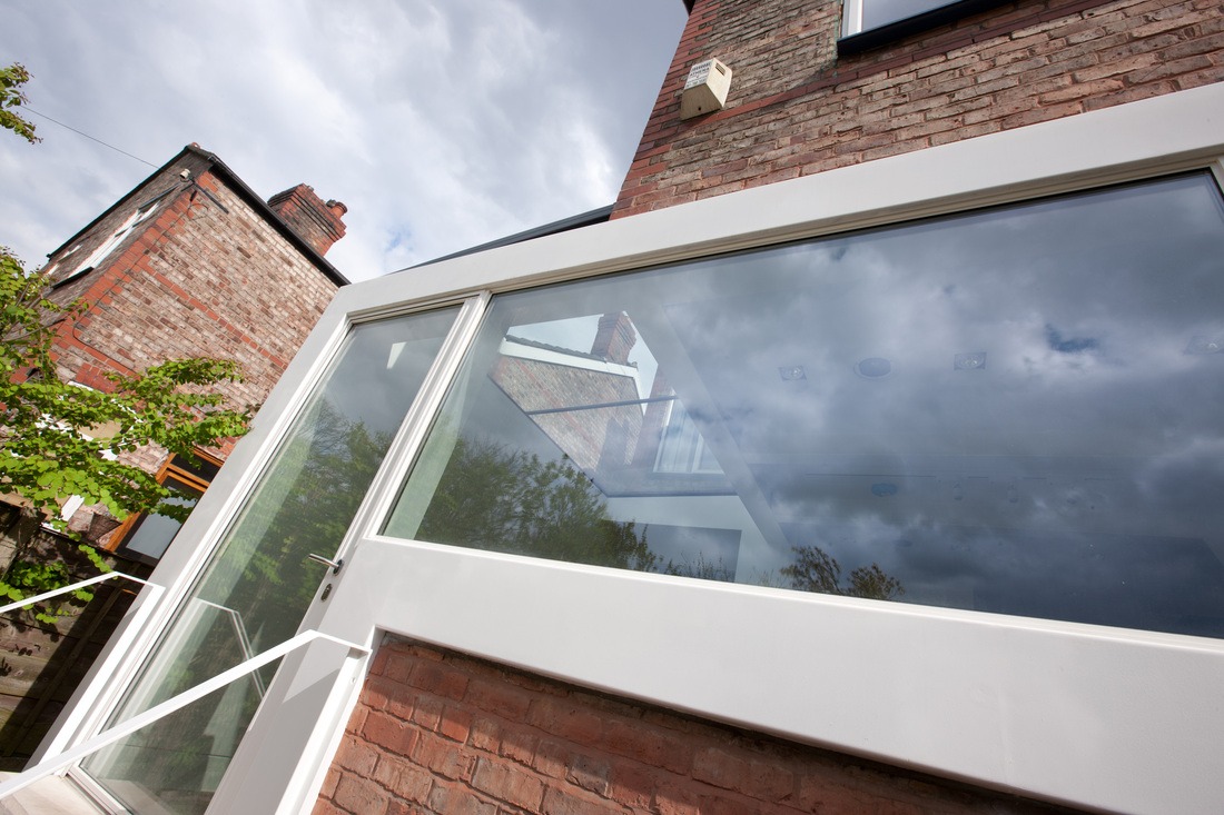 Close up of the crisp white frame of the extension against the brick house
