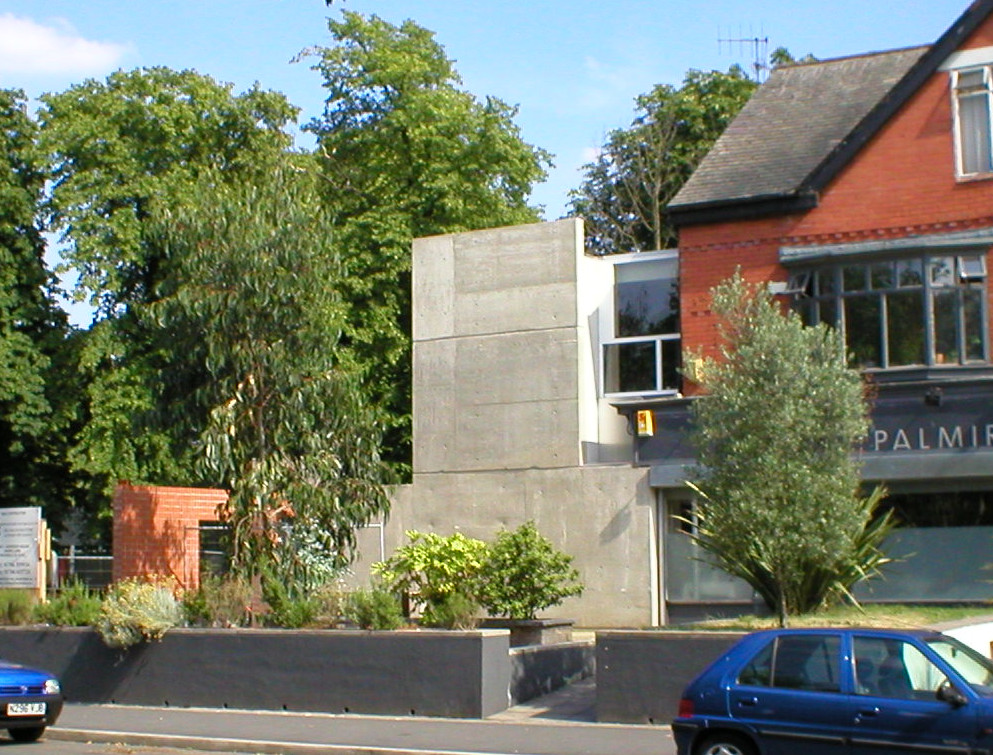 Front elevation from across the street — concrete tower, brick, planting