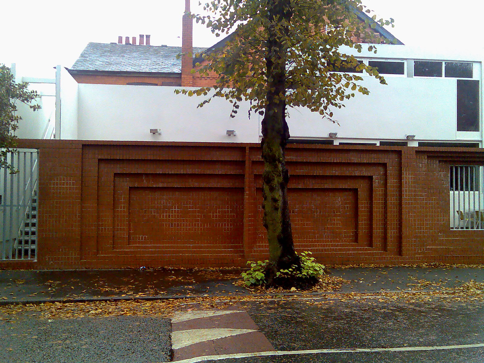 Rear elevation — brick boundary wall with recessed panels, tree, white render above