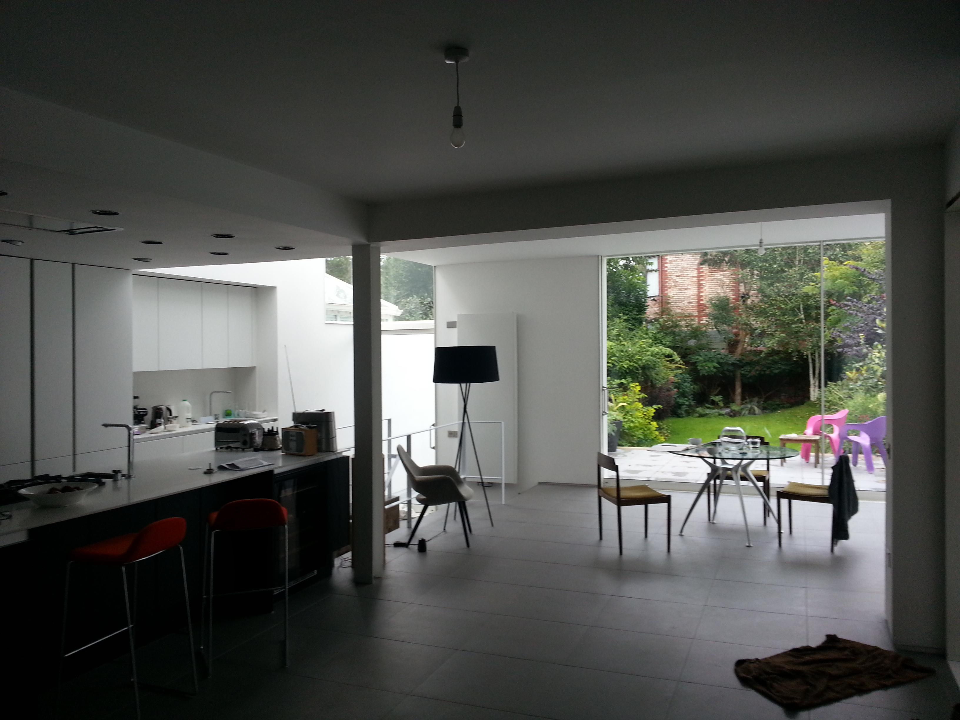 Wide view looking out from the dark kitchen toward the bright garden