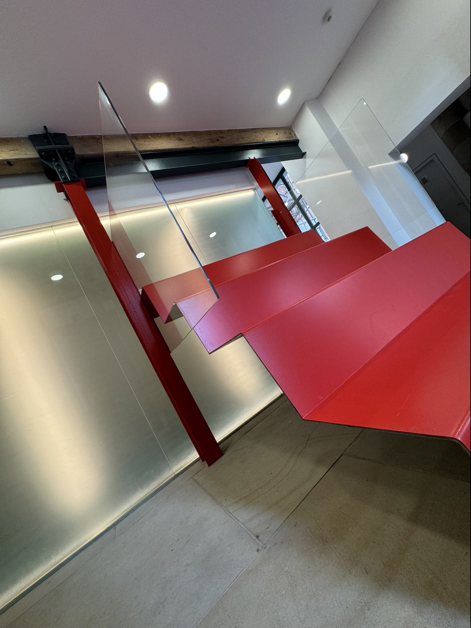 Red steel raked seating behind translucent glass screen